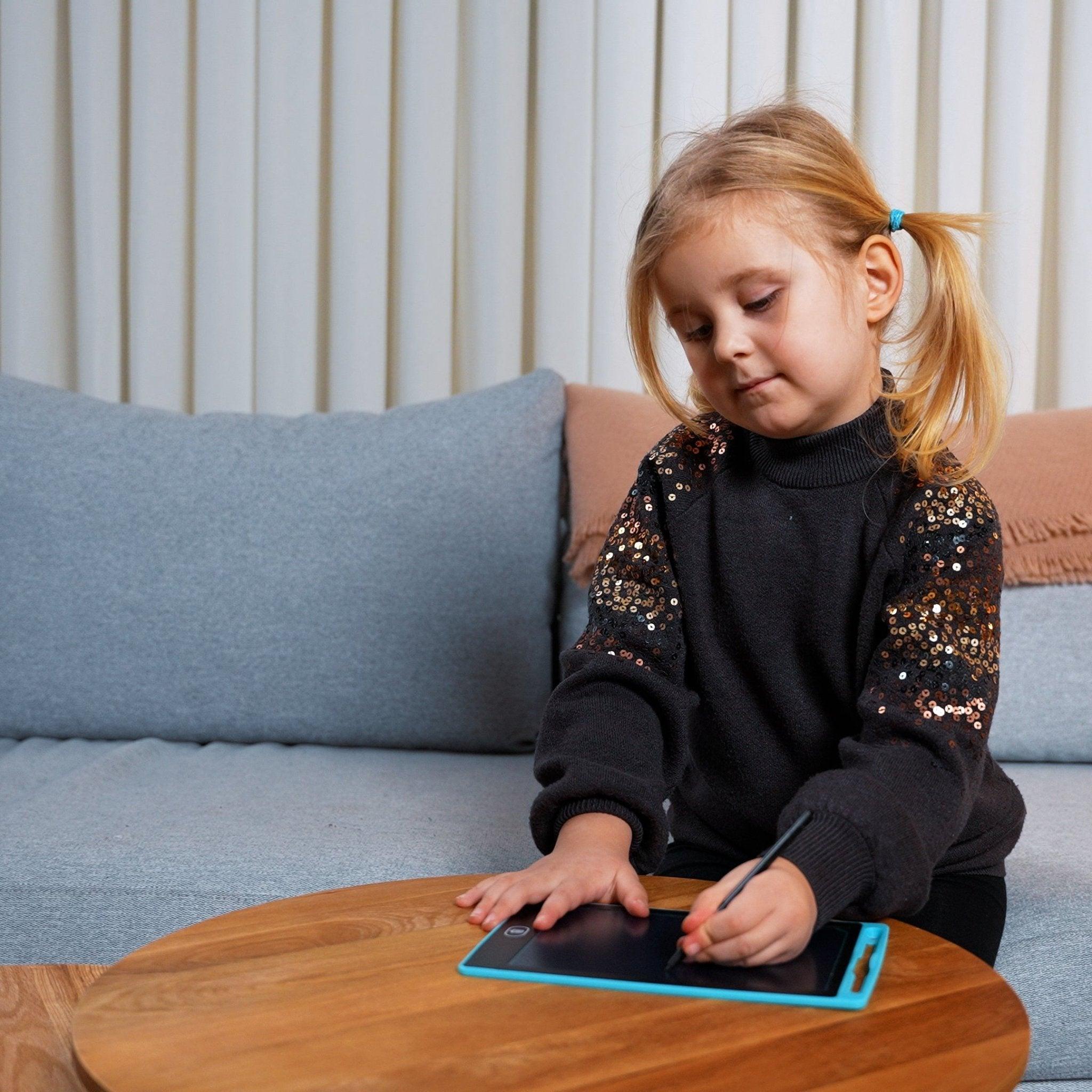 Barn der tegner med tegnepen på en lyseblå LCD tegnetablet ved et sofabord